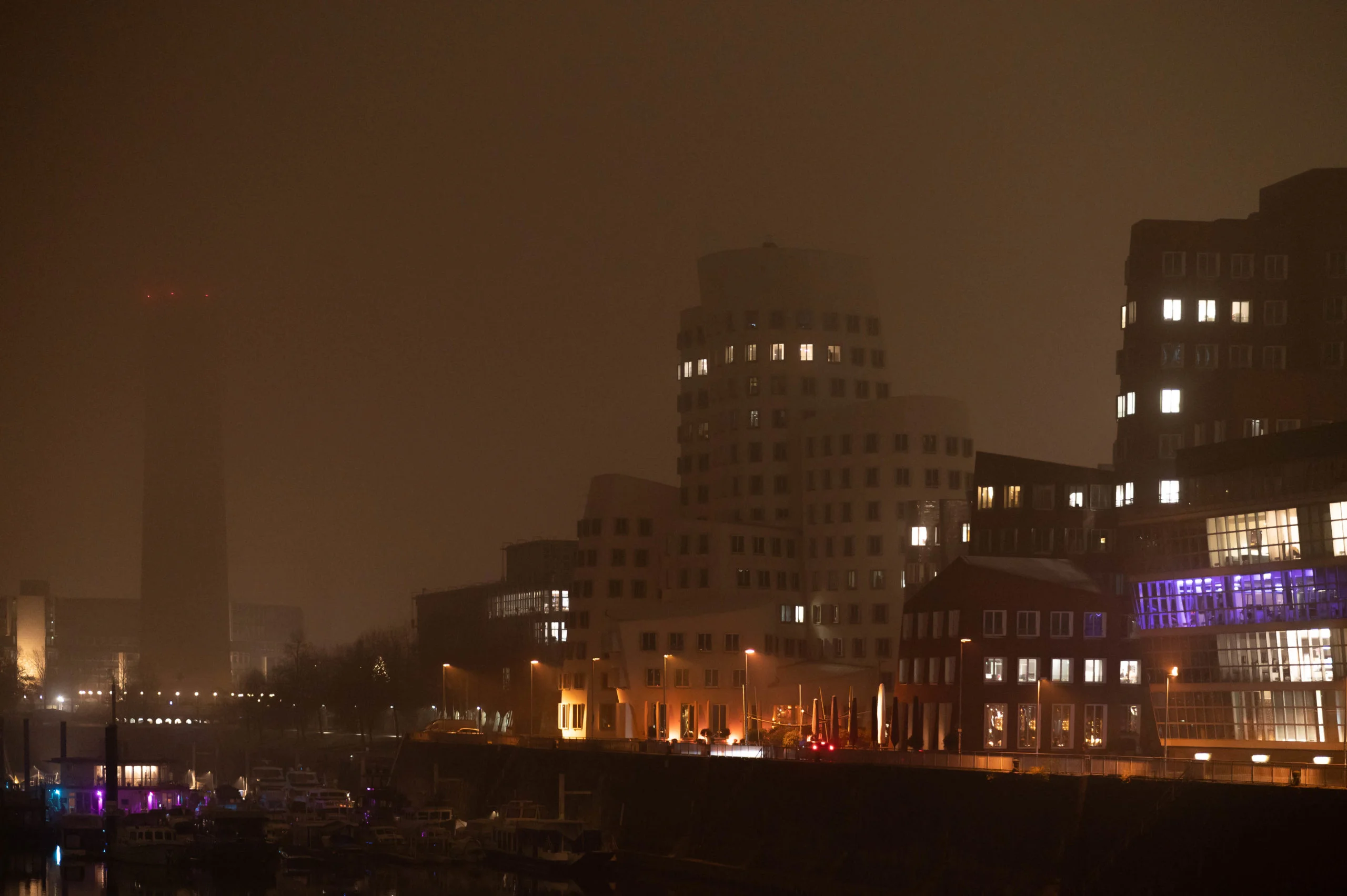 Neuer Zollhof, Frank Gehry mit Rheinturm in Düsseldorf. Bei Nacht im Nebel. Architekturfotografie.