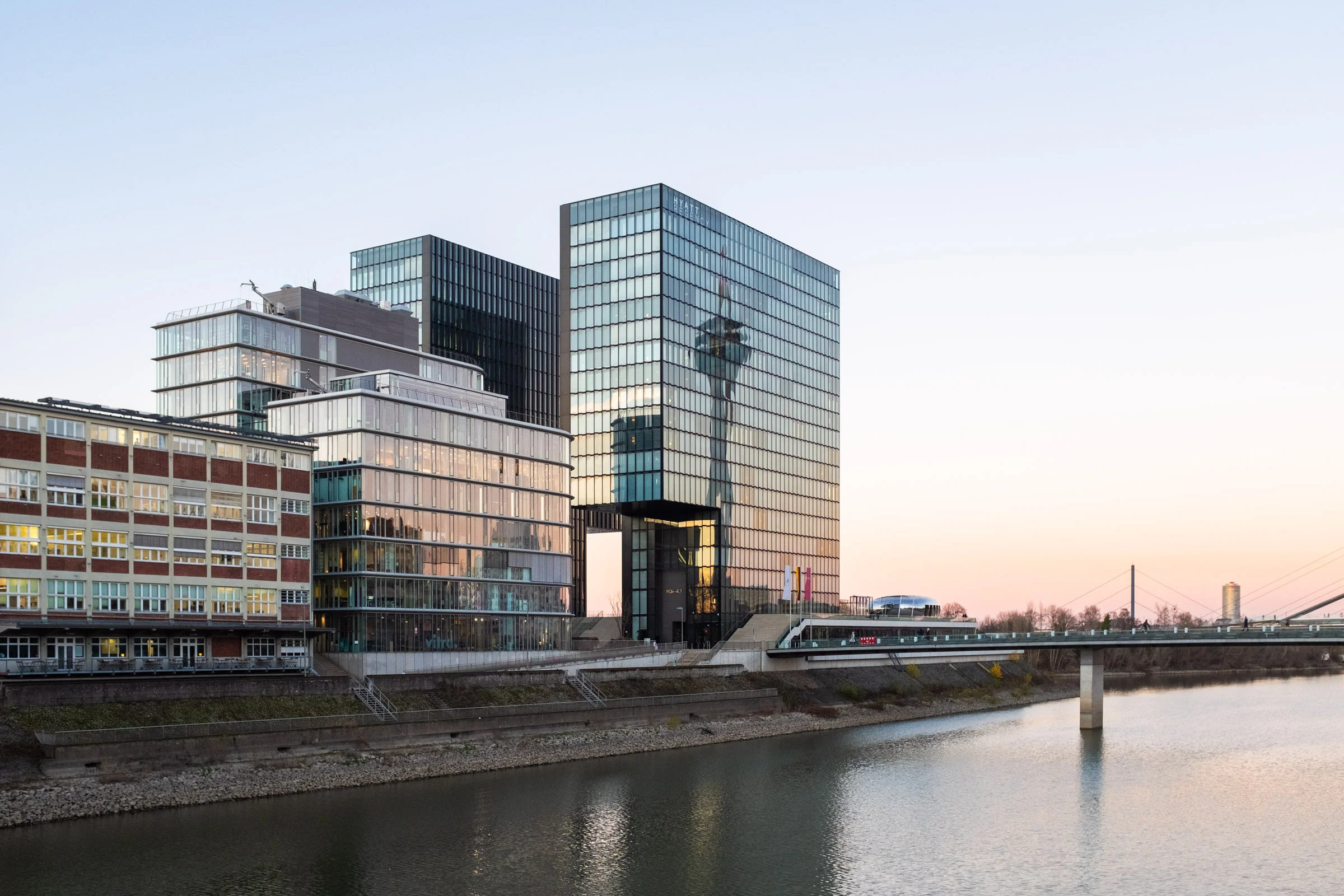 Blick vom Medienhafen quer zum Hochhaus Hyatt. Der Rheinturm spiegelt sich in der Fassade des Hotels. Rechts fließt der Rhein in Düsseldorf