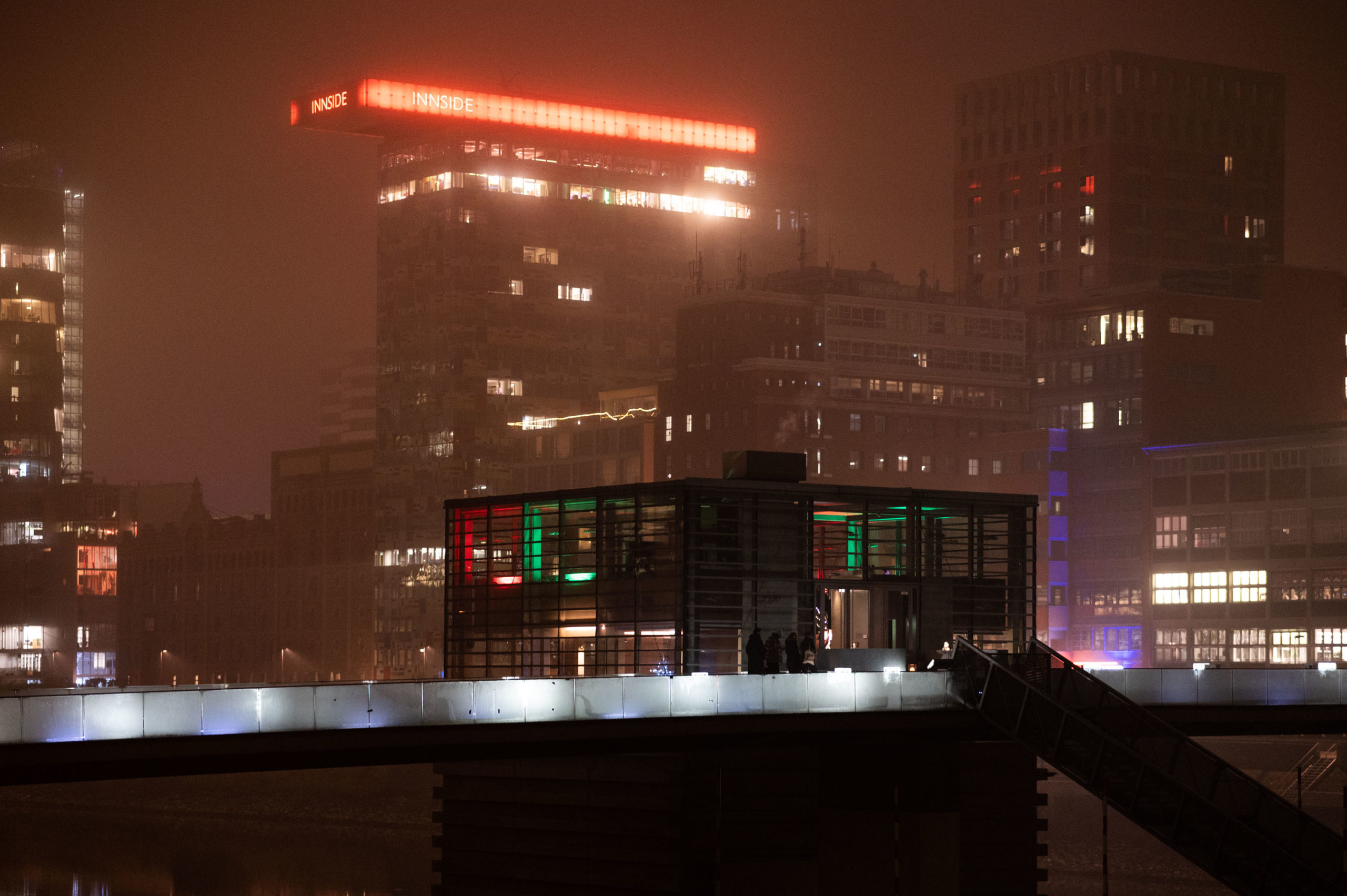 Medienhafen Düsseldorf Architektur bei Nacht. Im Hintergrund im nebel ist das Colorium sichtbar. Vorne ist das Restaurant Lido an der Brücke.